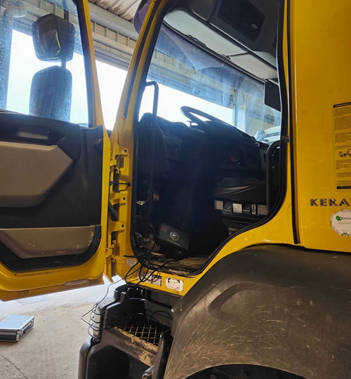 Vue de l’intérieur d’un camion jaune avec la porte ouverte, montrant le processus de reprogrammation