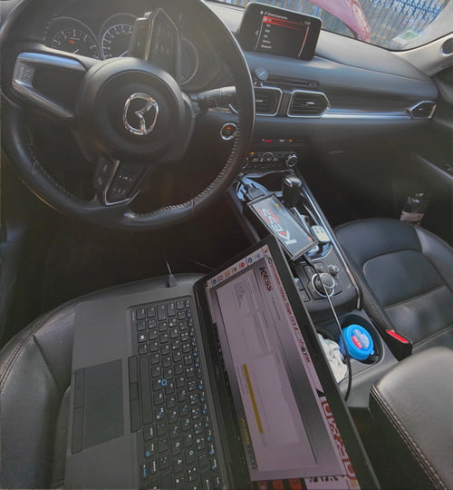 Un ordinateur portable connecté à la console d’une voiture pour la reprogrammation du moteur.