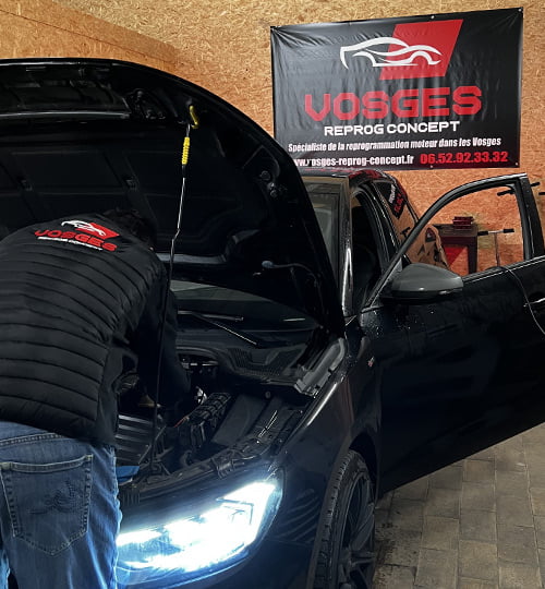 Un technicien effectue une reprogrammation moteur sur une voiture noire dans l’atelier de Vosges Reprog Concept.